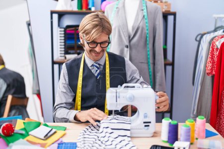 Photo for Young blond man tailor smiling confident using sewing machine at clothing factory - Royalty Free Image
