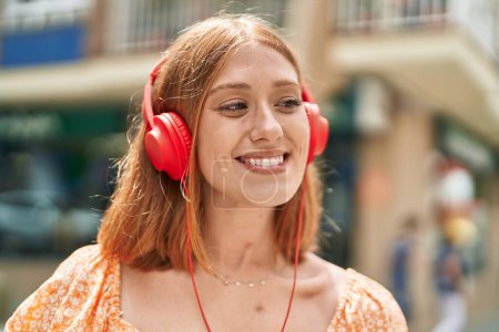 Téléchargez les photos : Young redhead woman smiling confident listening to music at street - en image libre de droit