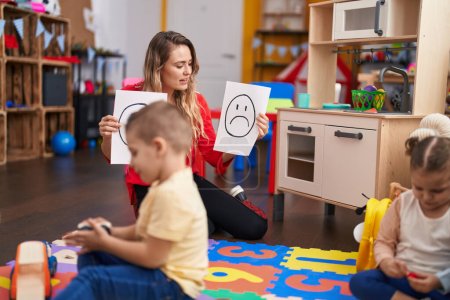 Téléchargez les photos : Professeur avec garçon et fille assis sur la table ayant une thérapie émotionnelle à la maternelle - en image libre de droit