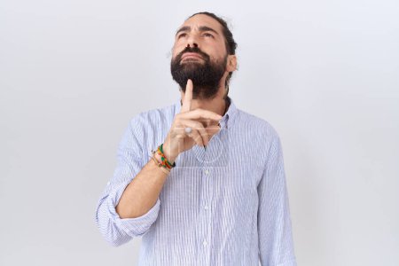 Photo for Hispanic man with beard wearing casual shirt thinking concentrated about doubt with finger on chin and looking up wondering - Royalty Free Image