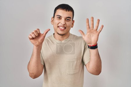 Foto de Hombre árabe joven con camiseta casual mostrando y señalando con los dedos número seis mientras sonríe confiado y feliz. - Imagen libre de derechos