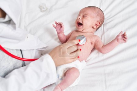 Téléchargez les photos : Adorable bébé caucasien ayant examen cardiaque avec stéthoscope pleurer à la chambre - en image libre de droit