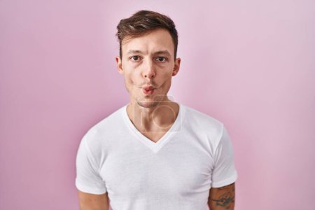 Photo for Caucasian man standing over pink background making fish face with lips, crazy and comical gesture. funny expression. - Royalty Free Image