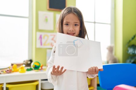 Photo for Adorable hispanic girl preschool student holding draw at kindergarten - Royalty Free Image
