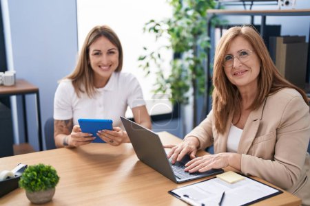 Photo for Mother and daughter business workers using laptop and touchpad working at office - Royalty Free Image
