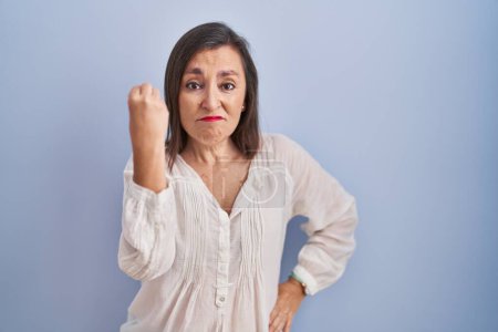Photo for Middle age hispanic woman standing over blue background doing italian gesture with hand and fingers confident expression - Royalty Free Image