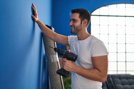 Téléchargez les photos : Jeune homme hispanique souriant confiant tenant exercice à la nouvelle maison - en image libre de droit