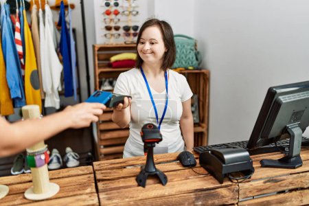 Photo for Brunette woman with down syndrome working as shop assistant taking payment at retail shop - Royalty Free Image