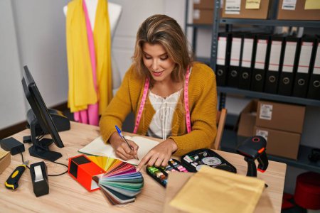 Téléchargez les photos : Young blonde woman dressmaker choosing cloth color at designer studio - en image libre de droit