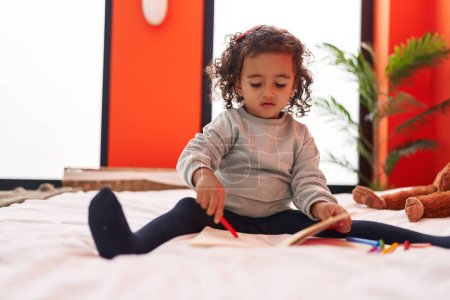 Photo for Adorable hispanic girl drawing on notebook sitting on sofa at bedroom - Royalty Free Image