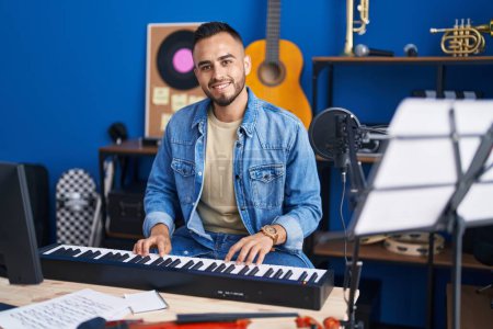 Foto de Joven músico hispano tocando el teclado de piano en el estudio de música - Imagen libre de derechos
