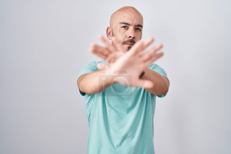 Foto de Middle age bald man standing over white background rejection expression crossing arms and palms doing negative sign, angry face - Imagen libre de derechos