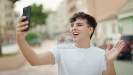 Téléchargez les photos : Homme non binaire souriant confiant ayant appel vidéo au parc - en image libre de droit