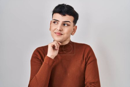 Photo for Non binary person wearing make up standing over isolated background serious face thinking about question with hand on chin, thoughtful about confusing idea - Royalty Free Image