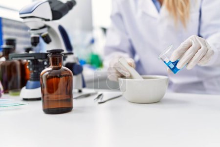 Téléchargez les photos : Jeune femme blonde portant l'uniforme de scientifique travaillant au laboratoire - en image libre de droit