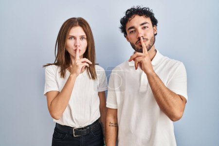 Photo for Young couple wearing casual clothes standing together asking to be quiet with finger on lips. silence and secret concept. - Royalty Free Image