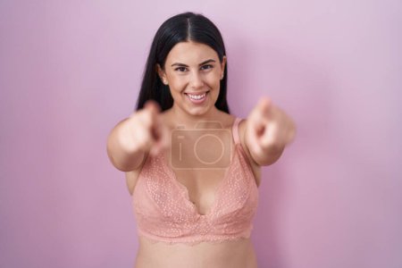 Photo for Young hispanic woman wearing pink bra pointing to you and the camera with fingers, smiling positive and cheerful - Royalty Free Image