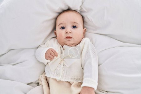 Téléchargez les photos : Adorable bébé détendu couché sur le lit dans la chambre - en image libre de droit