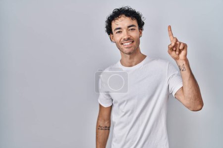 Téléchargez les photos : Hispanic man standing over isolated background showing and pointing up with finger number one while smiling confident and happy. - en image libre de droit
