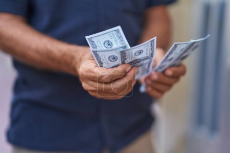 Téléchargez les photos : Middle age man counting dollars at street - en image libre de droit