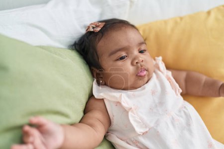 Photo for African american baby sitting on bed with relaxed expression at bedroom - Royalty Free Image