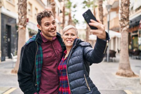 Foto de Madre e hijo sonriendo confiados haciendo selfie por el teléfono inteligente en la calle - Imagen libre de derechos