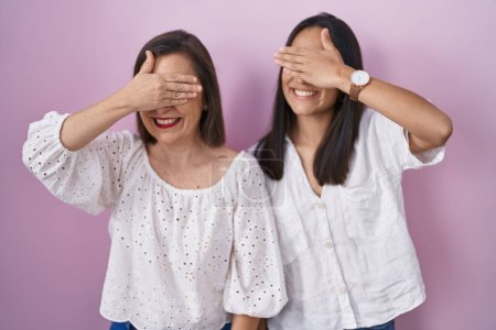Téléchargez les photos : Hispanic mother and daughter together smiling and laughing with hand on face covering eyes for surprise. blind concept. - en image libre de droit