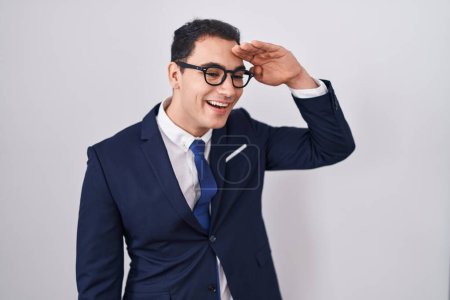 Photo for Young hispanic man wearing suit and tie very happy and smiling looking far away with hand over head. searching concept. - Royalty Free Image