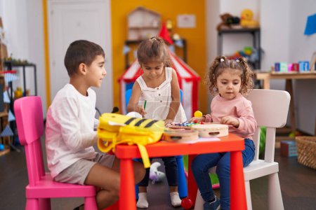 Foto de Grupo de niños estudiantes de preescolar sentados en un dibujo de mesa sobre papel en el jardín de infantes - Imagen libre de derechos