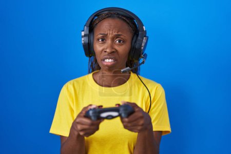 Photo for African american woman playing video games clueless and confused expression. doubt concept. - Royalty Free Image