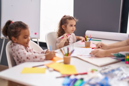 Foto de Dos niños preescolares sentados en la mesa dibujando sobre papel en el aula - Imagen libre de derechos