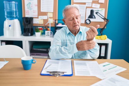 Téléchargez les photos : Middle age grey-haired man business worker suffering for wrist pain working at office - en image libre de droit