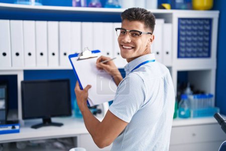 Photo for Young hispanic man scientist writing on document at laboratory - Royalty Free Image