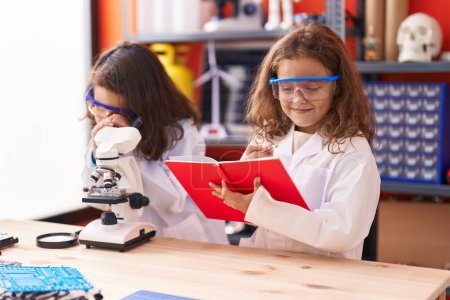 Photo for Two kids students using microscope writing on notebook at laboratory classroom - Royalty Free Image