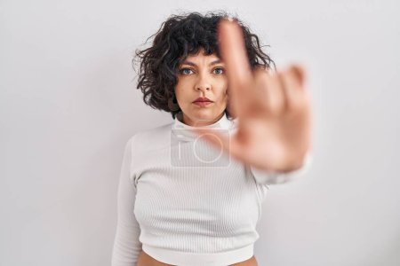 Foto de Hispanic woman with curly hair standing over isolated background pointing with finger up and angry expression, showing no gesture - Imagen libre de derechos