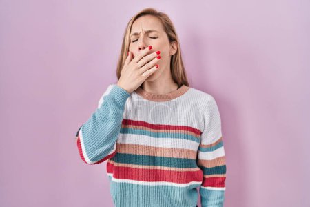 Téléchargez les photos : Young blonde woman standing over pink background bored yawning tired covering mouth with hand. restless and sleepiness. - en image libre de droit