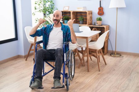 Photo for Hispanic man with beard sitting on wheelchair holding new house keys pointing thumb up to the side smiling happy with open mouth - Royalty Free Image