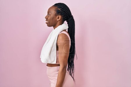 Photo for Beautiful black woman wearing sportswear and towel over pink background looking to side, relax profile pose with natural face with confident smile. - Royalty Free Image