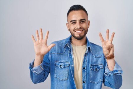 Photo for Young hispanic man standing over isolated background showing and pointing up with fingers number eight while smiling confident and happy. - Royalty Free Image