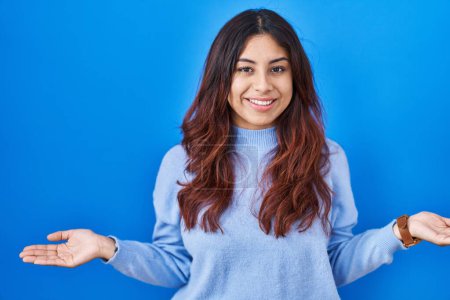 Photo for Hispanic young woman standing over blue background clueless and confused with open arms, no idea concept. - Royalty Free Image