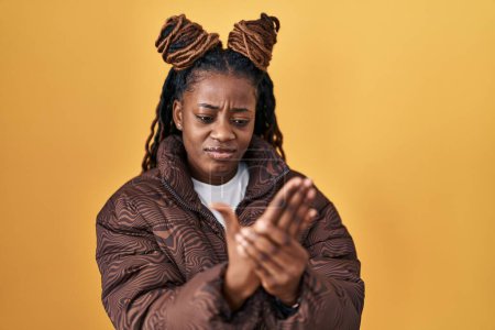 Photo for African woman with braided hair standing over yellow background suffering pain on hands and fingers, arthritis inflammation - Royalty Free Image