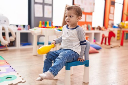 Téléchargez les photos : Adorable garçon caucasien jouant avec pin bowling assis sur la chaise à la maternelle - en image libre de droit