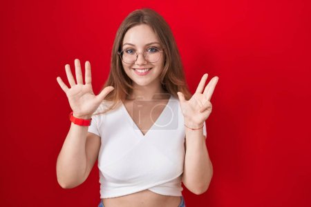 Téléchargez les photos : Young caucasian woman standing over red background showing and pointing up with fingers number nine while smiling confident and happy. - en image libre de droit
