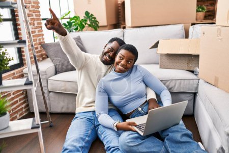Téléchargez les photos : Homme et femme couple en utilisant ordinateur portable assis sur le sol à la nouvelle maison - en image libre de droit