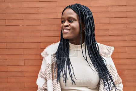 Téléchargez les photos : African american woman smiling confident looking to the side over isolated brick background - en image libre de droit