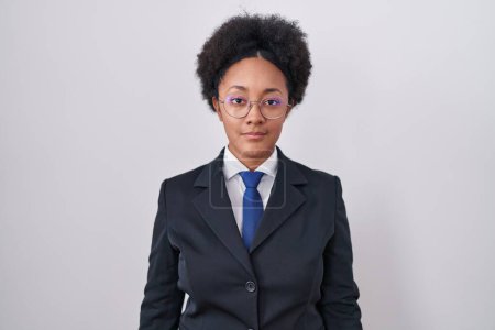 Photo for Beautiful african woman with curly hair wearing business jacket and glasses relaxed with serious expression on face. simple and natural looking at the camera. - Royalty Free Image