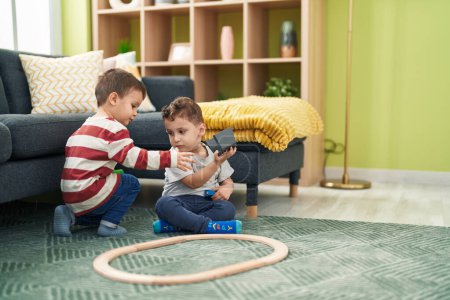 Foto de Dos niños jugando con el juguete del tren sentados en el suelo en casa - Imagen libre de derechos