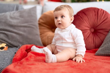 Photo for Adorable toddler sitting on sofa with relaxed expression at home - Royalty Free Image