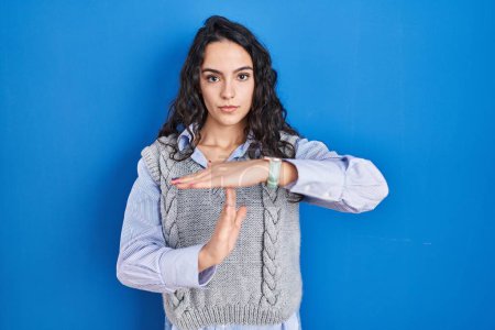 Téléchargez les photos : Jeune femme brune debout sur fond bleu faisant un geste avec les mains, frustré et sérieux visage - en image libre de droit
