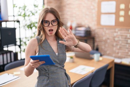 Photo for Caucasian woman working at the office wearing glasses doing stop gesture with hands palms, angry and frustration expression - Royalty Free Image